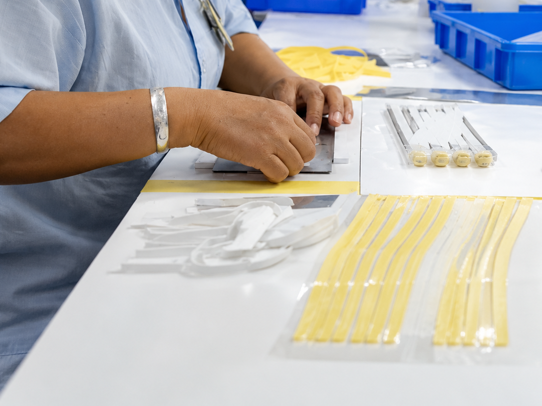 Hands assembling flexible printed circuits at a cleanroom bench